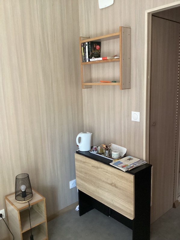 A room with a wooden desk, a bookshelf, and a small table with a lamp.