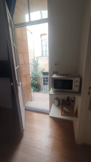 Eine Küche mit Mikrowelle, einer kleinen Ablage für Küchenutensilien und Blick auf den Balkon.