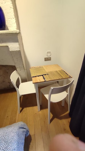 Ein kleines Zimmer mit einem Holztisch und zwei weißen Stühlen.