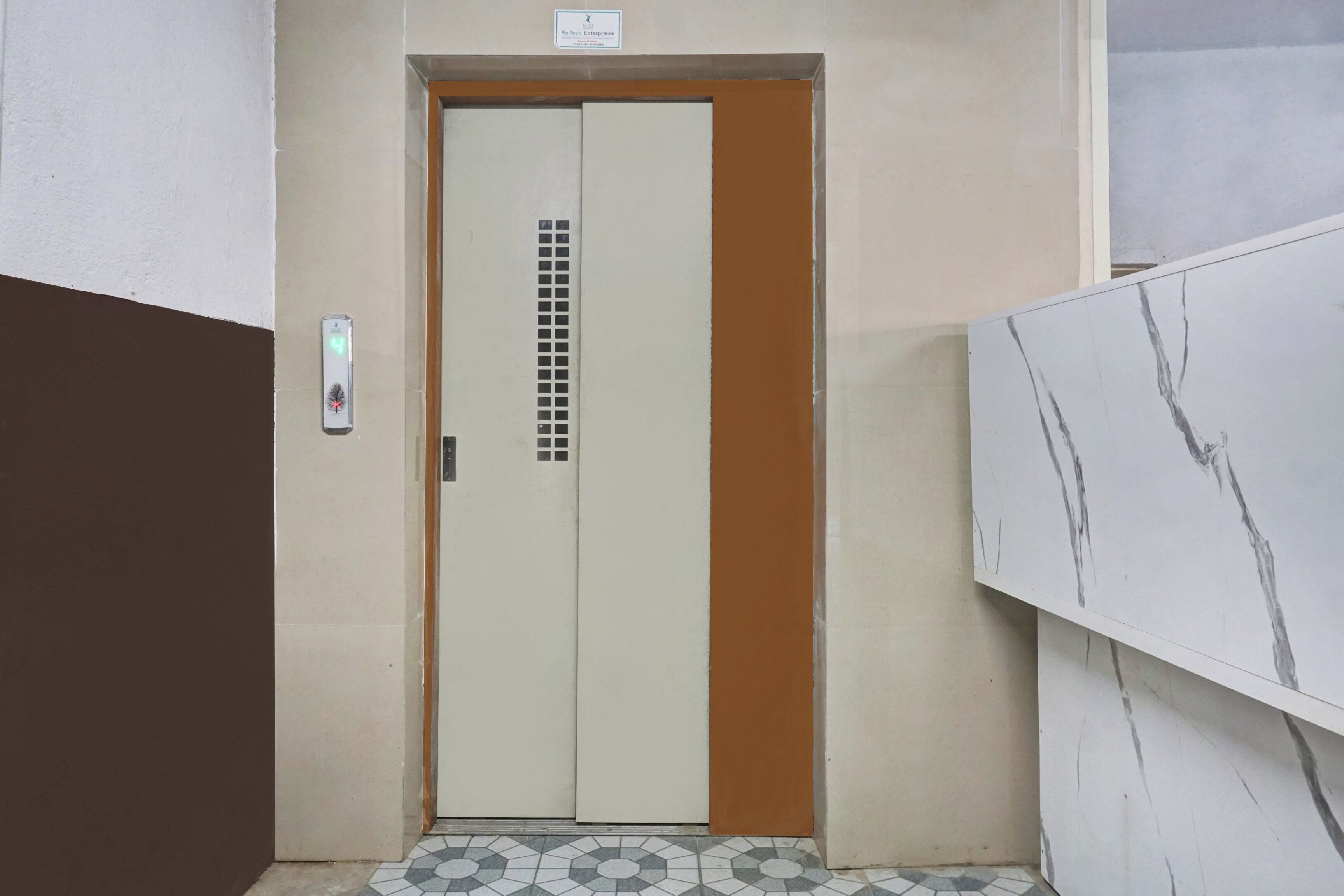 Une porte dotée d’un écran numérique, un sol carrelé et un mur en marbre.