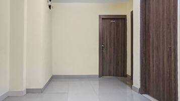 A hallway with a tiled floor, a wooden door with the number 204, and a wall-mounted electrical outlet.