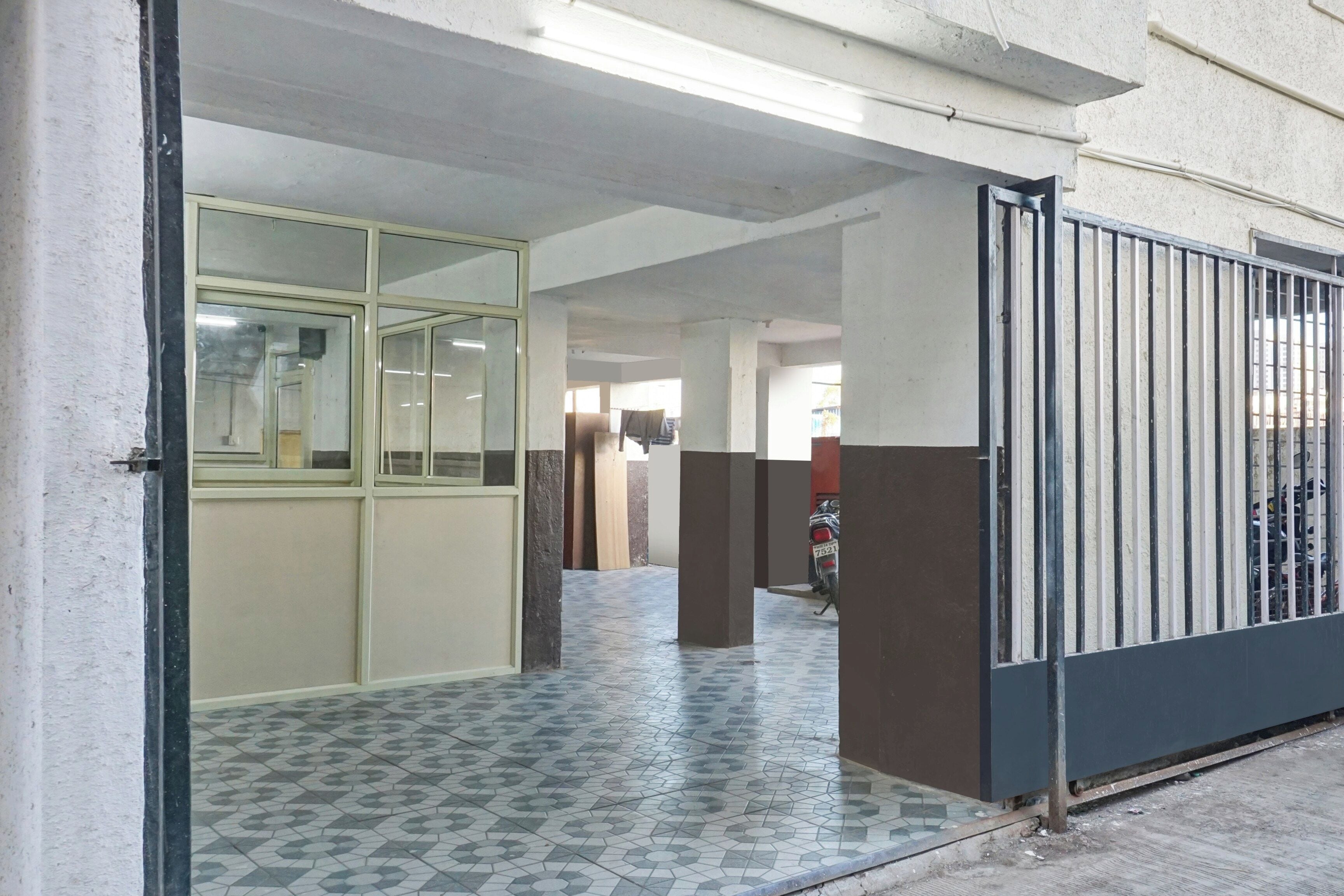 Un pasillo con suelo de baldosas, una puerta de cristal y una reja de metal.