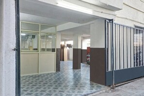 A hallway with tiled flooring, a glass door, and a metal gate. - Hotel O Sai Avenue (Paud)