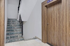 A staircase with marble steps leading to a wooden door with a sign above it. - Hotel O Sai Avenue (Paud)