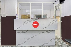 A reception desk with a marble design and a red logo. - Hotel O Sai Avenue (Paud)