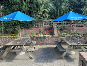 Terraza al aire libre con sombrillas azules y paredes de ladrillo.