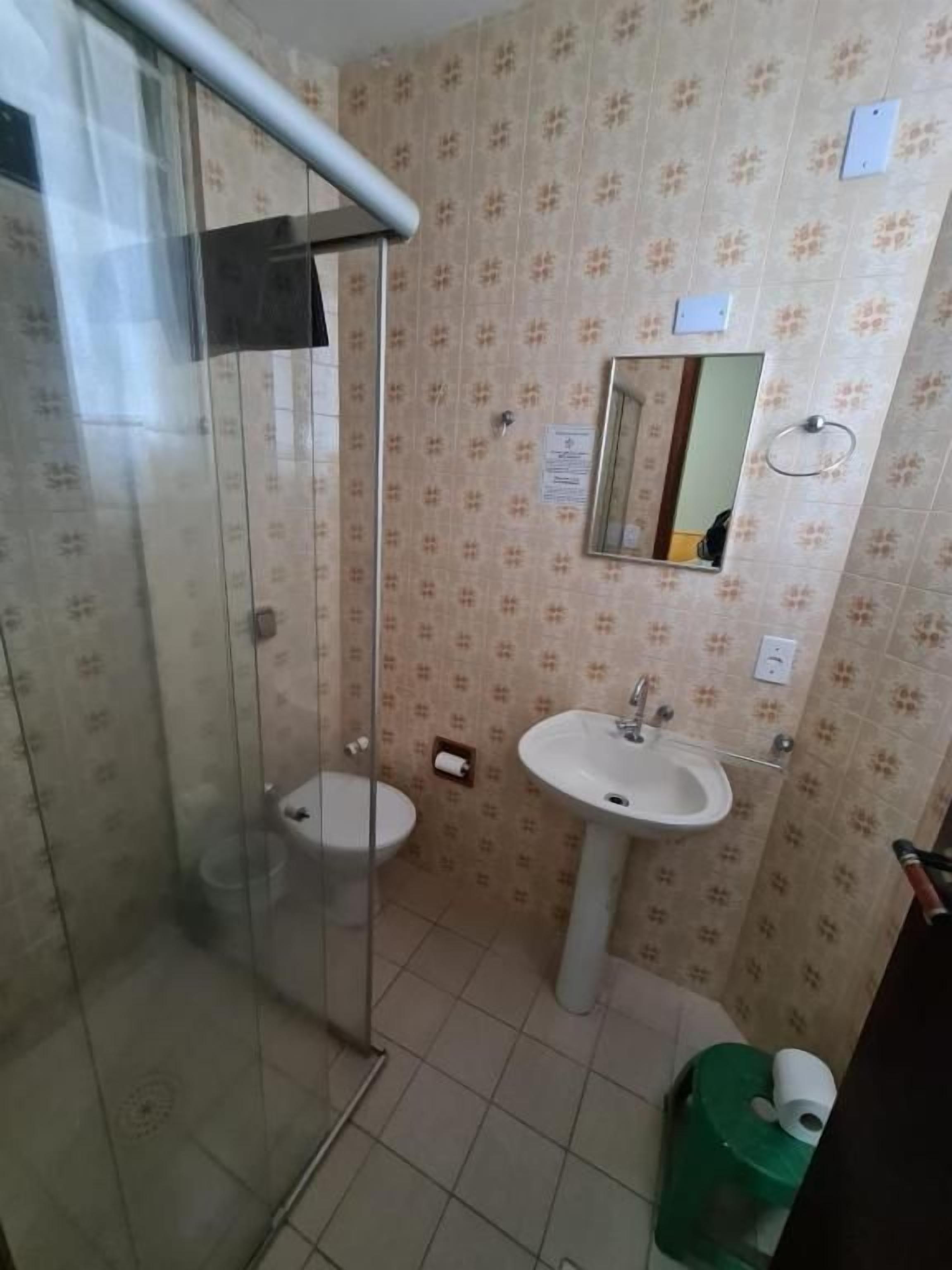 Un baño con cabina de ducha de vidrio, inodoro, lavabo y espejo.
