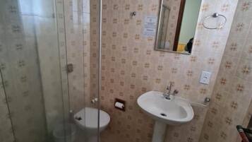 Un baño con cabina de ducha de vidrio, inodoro, lavabo y espejo.