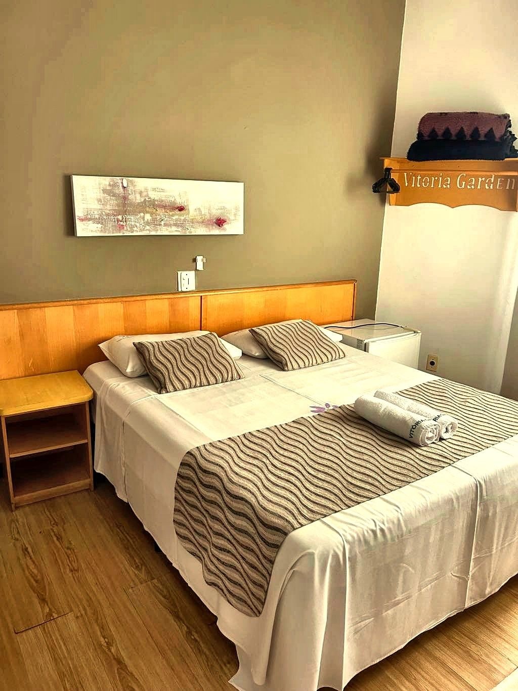 Habitación de hotel con cama, mesita de noche y una obra de arte colgada en la pared.
