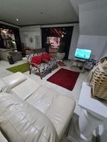 A modern living room with a sofa set, a television, and a dining area.