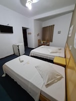 A hotel room with two beds, a desk, a chair, a small table, and a television on the wall.