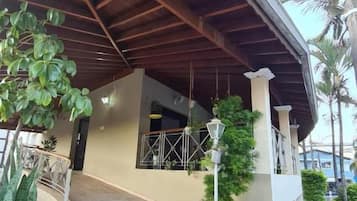 Un espace extérieur abrité, doté d’un sol carrelé, de plantes en pot et d’une structure de plafond en bois.