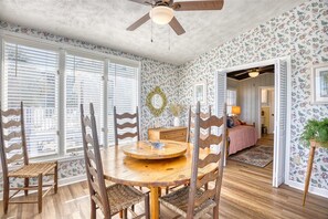 A dining area with a round wooden table, four chairs, and a ceiling fan. - Toddle House- 5 Bds- Slps 10- dogs ok- canal view (North Myrtle Beach)
