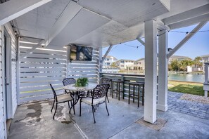 An outdoor patio with a table and chairs, a view of a body of water, and a building in the background. - Toddle House- 5 Bds- Slps 10- dogs ok- canal view (North Myrtle Beach)