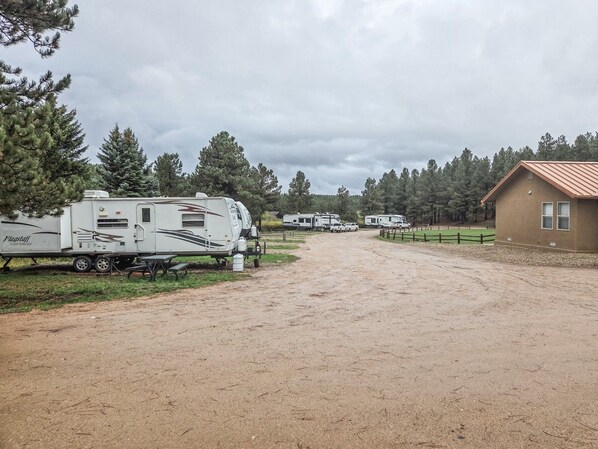 A campground with RVs, a dirt road, and a building with a red roof. - Angel Fire Alpine Retreat (Angel Fire)