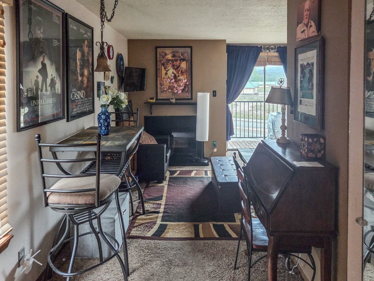 Een woonkamer met een open haard, een eethoek met stoelen en een tafel, en een balkon met uitzicht.