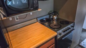 A compact kitchen with a microwave, kettle, stove, and oven.