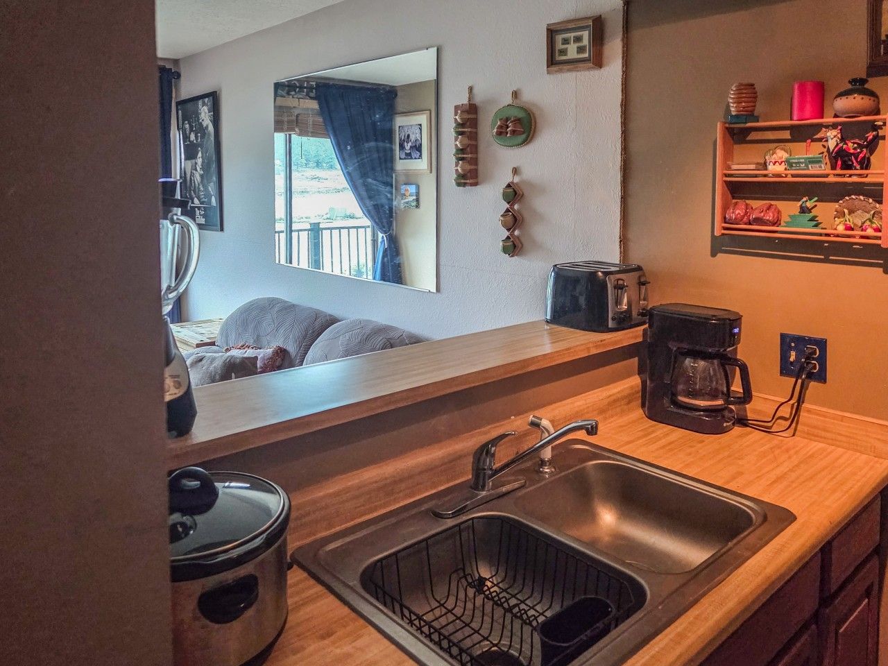 A compact kitchen with a sink, a coffee maker, and a toaster.