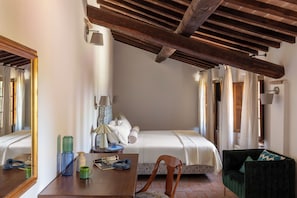 A bedroom with a bed, a wooden ceiling, a table with a lamp, and a chair. - Comfort and relaxation in the heart of the Crete Senesi (Toscana)