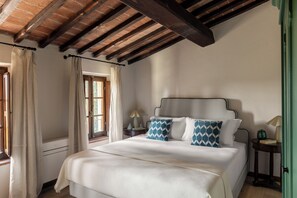 Ein Schlafzimmer mit einem Bett, einem Nachttisch, einer Lampe und einem Fenster mit Vorhängen.