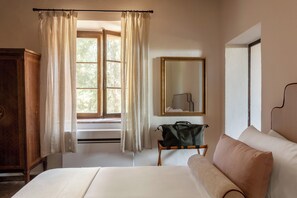 A bedroom with a bed, a dresser, a mirror, and a window with curtains. - Comfort and relaxation in the heart of the Crete Senesi (Toscana)