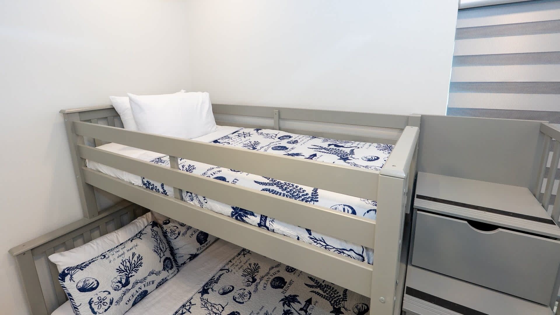 A bunk bed with a white mattress and blue patterned bedding.