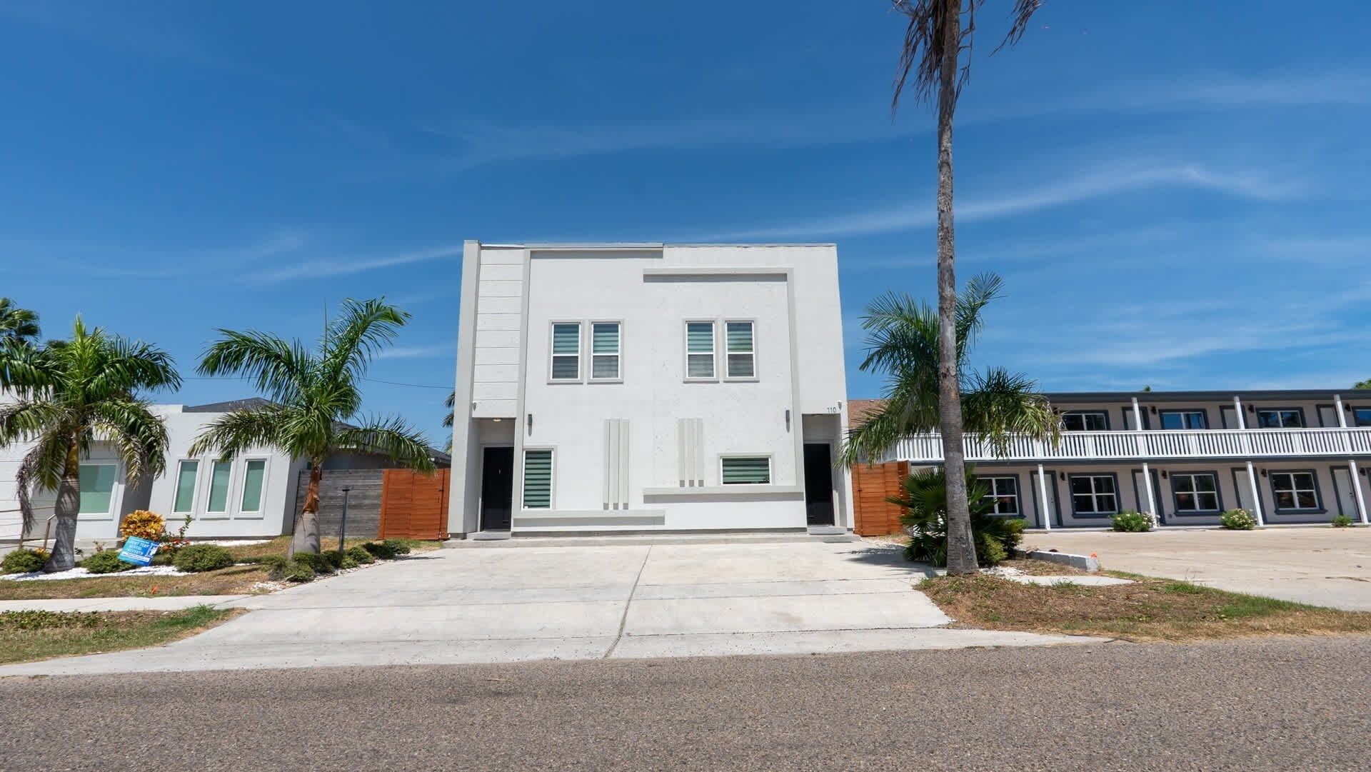 A modern two-story building with a flat roof, large windows, and a central entrance.