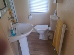 A bathroom with a sink, toilet, and a window. - Chapel Farm Holiday Park No 6 Bunnies View (Appleby-in-Westmorland)