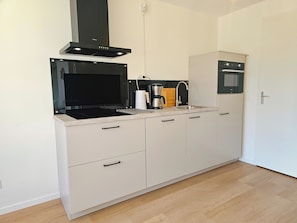 Eine moderne Küche mit Einbauherd, Kaffeemaschine und Mikrowelle.