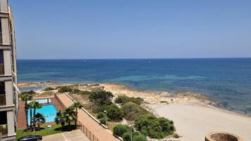 Blick auf die Küste mit Strand, klarem blauen Meer und einem Schwimmbad.