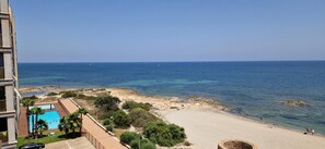 Blick auf die Küste mit Strand, klarem blauen Meer und einem Schwimmbad.