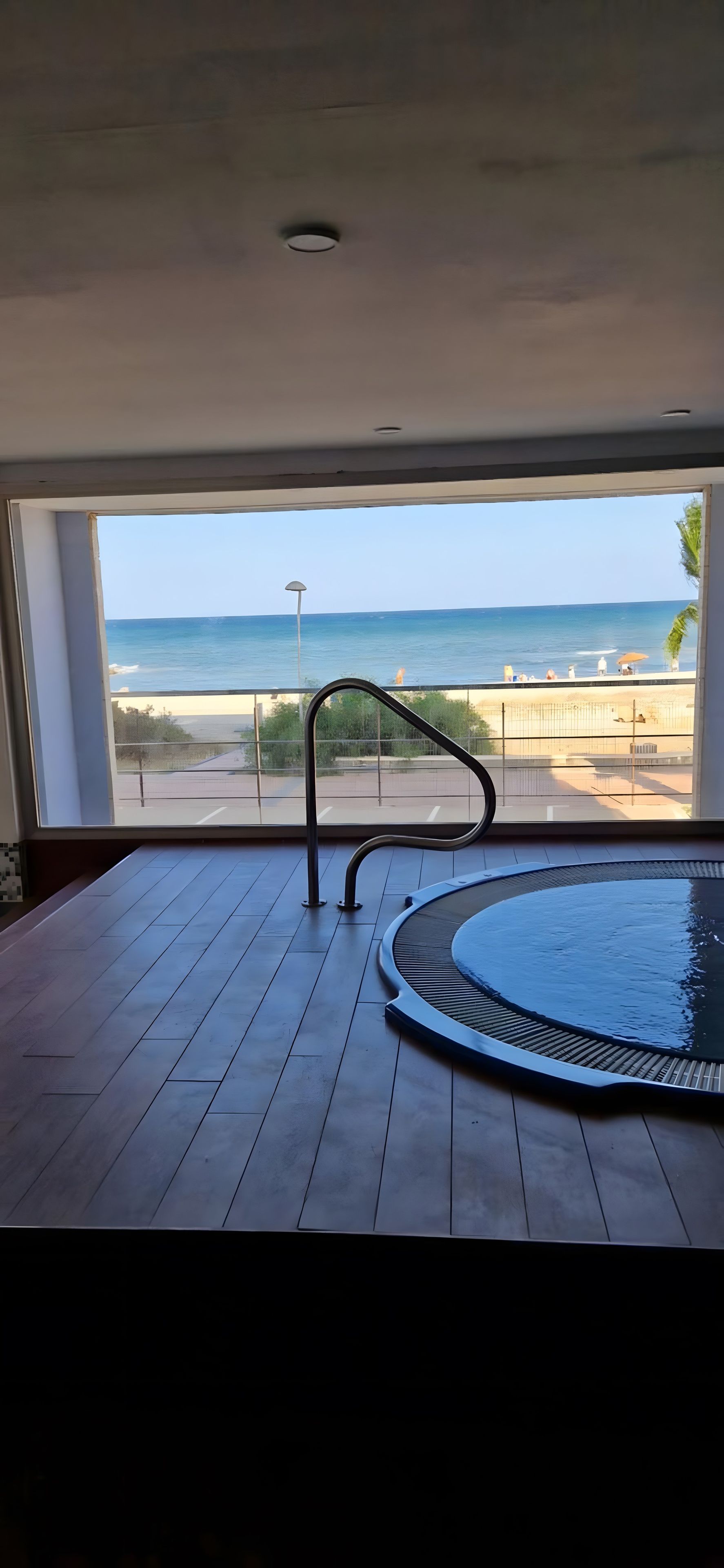 Une chambre avec vue sur la plage, une piscine et une rambarde en métal.