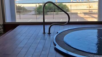 Une chambre avec vue sur la plage, une piscine et une rambarde en métal.