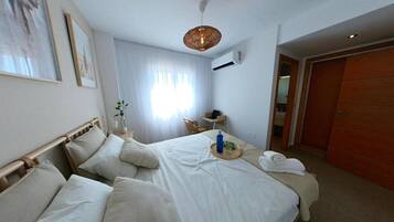 Una habitación de hotel con cama, mesita de noche, lámpara, ventana con cortinas y armario.