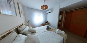Ein Hotelzimmer mit einem Bett, einem Nachttisch, einer Lampe, einem Fenster mit Vorhängen und einem Kleiderschrank.