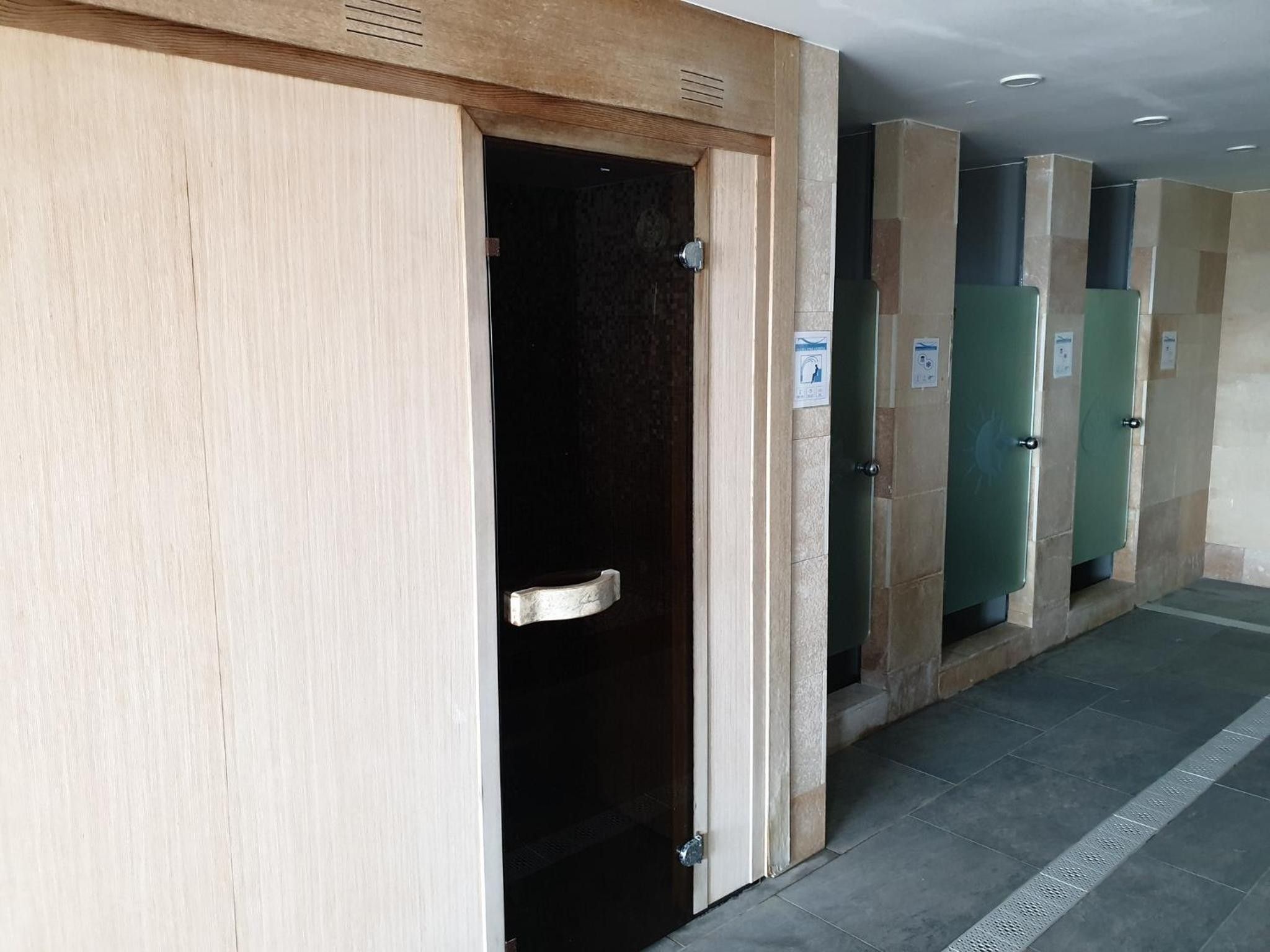 Une rangée de chambres d’hôtel avec des portes en bois et des planchers carrelés.