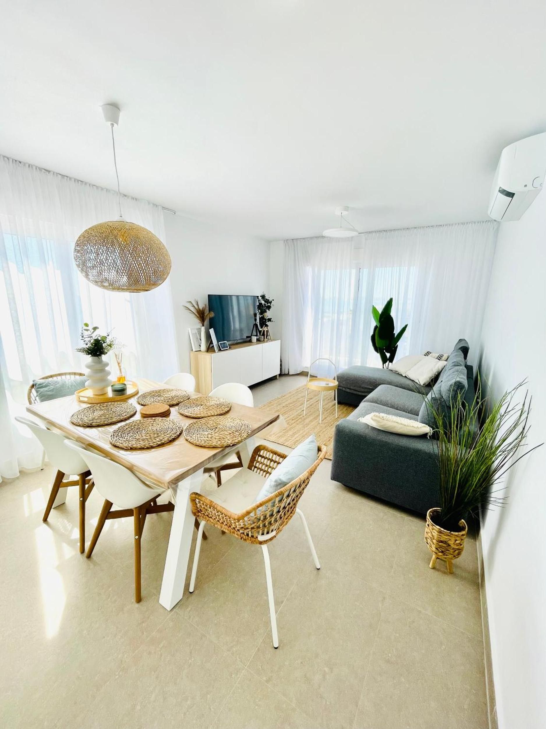 Un salon moderne avec un coin repas, comprenant un canapé, un téléviseur et une table à manger avec des chaises.