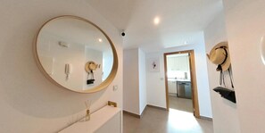 A hallway with a large mirror, a wall-mounted hat rack, and a door leading to a kitchen area. - Apartment 'Rokita Blanca' with Sea View, Wi-Fi and Air Conditioning (La Manga del Mar Menor)
