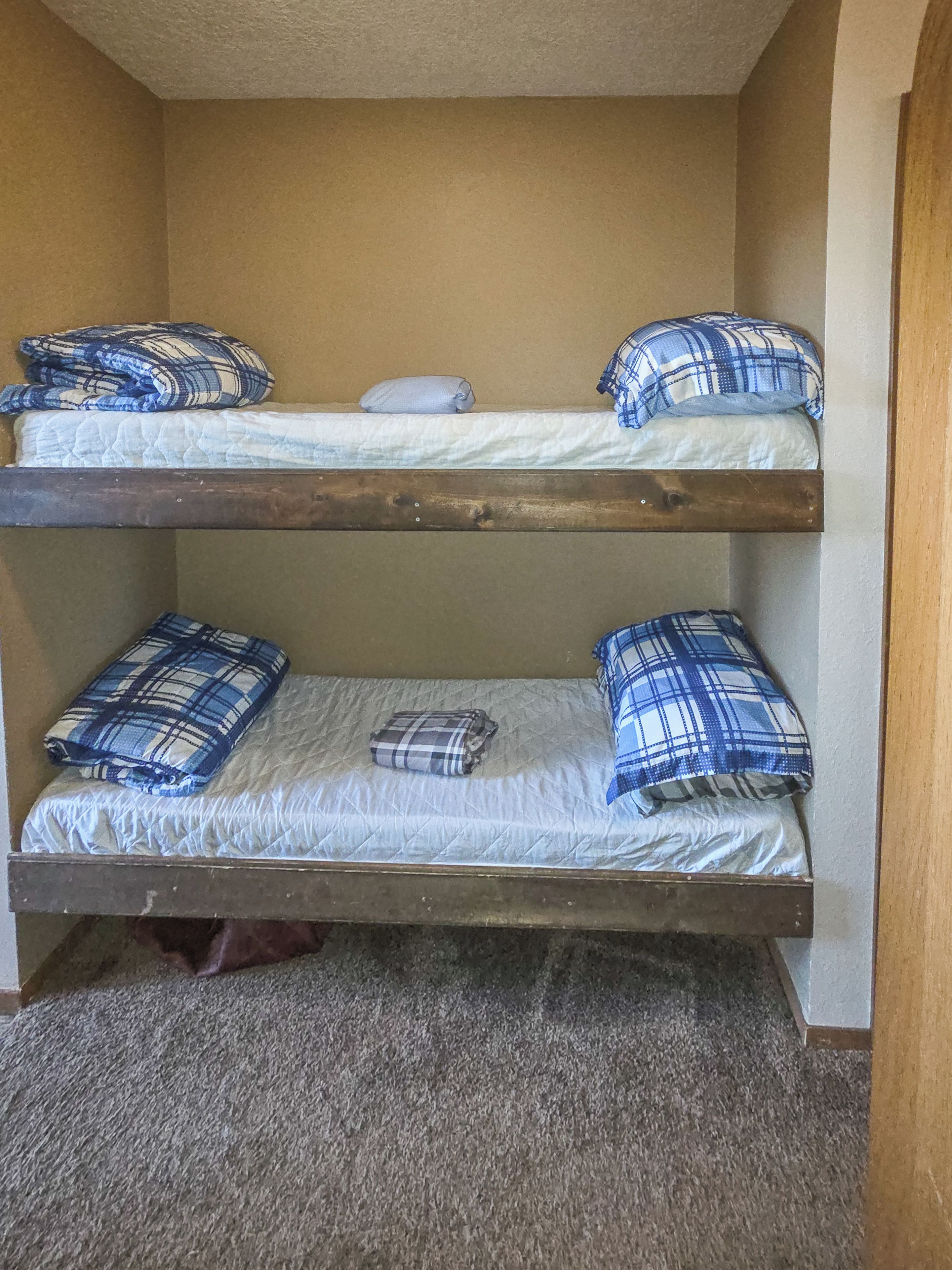 A bunk bed with two levels, each with a mattress and pillows.