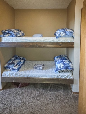 A bunk bed with two levels, each with a mattress and pillows.