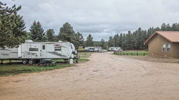 A gravel driveway leading to a row of RVs parked beside a building with a brown roof.