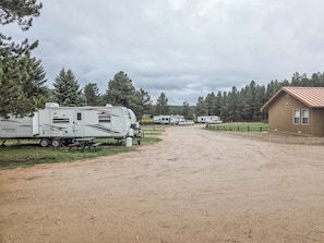 A gravel driveway leading to a row of RVs parked beside a building with a brown roof.