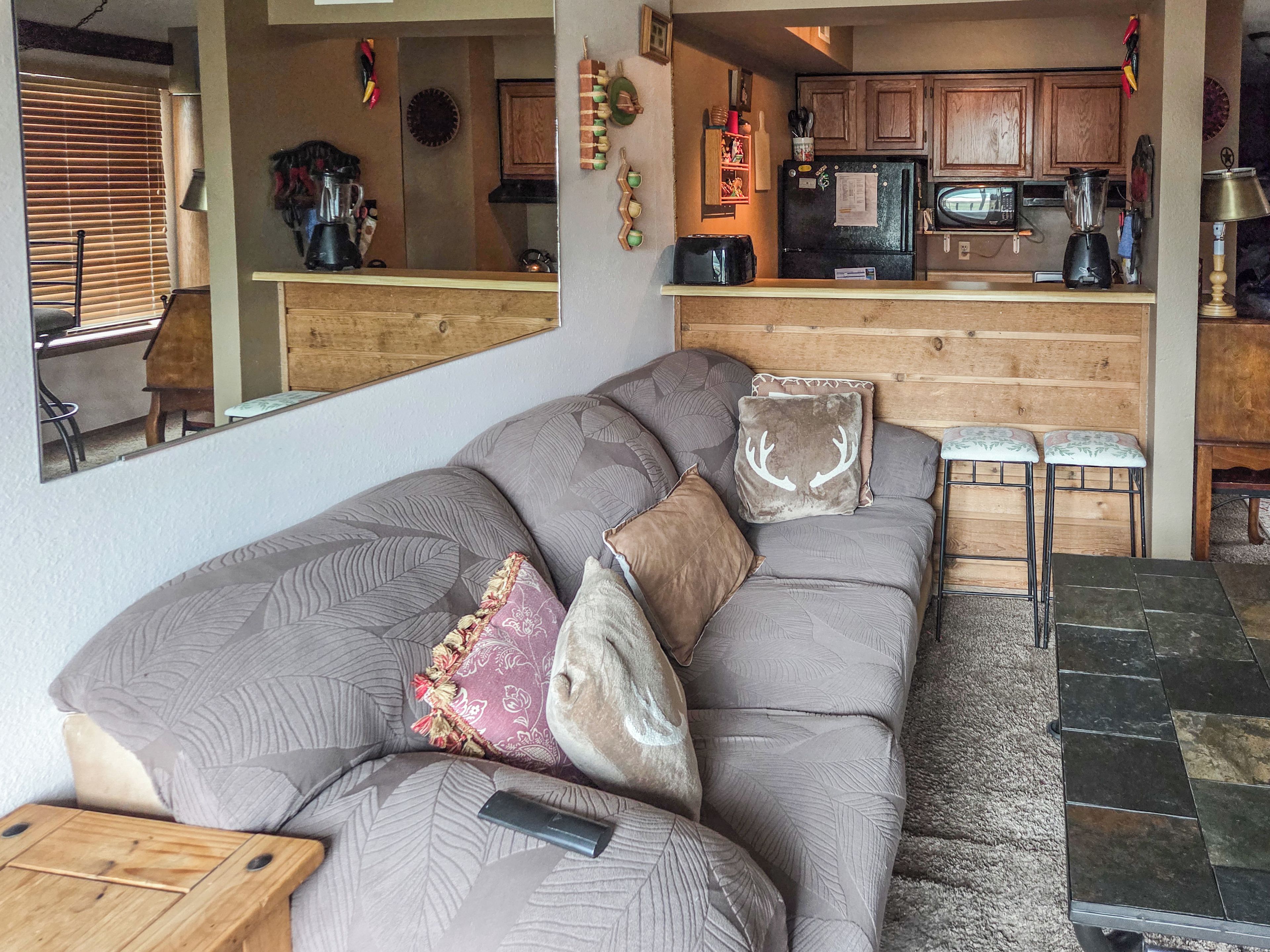 A living room with a sofa, a coffee table, and a kitchen area in the background.