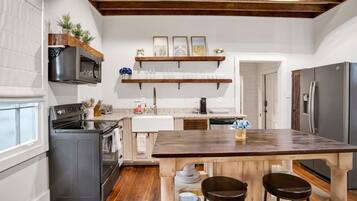 A kitchen with a central island, wooden beams on the ceiling, and a view to the dining area.