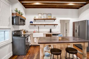 Una cocina con una isla central, vigas de madera en el techo y vistas al área de comedor.