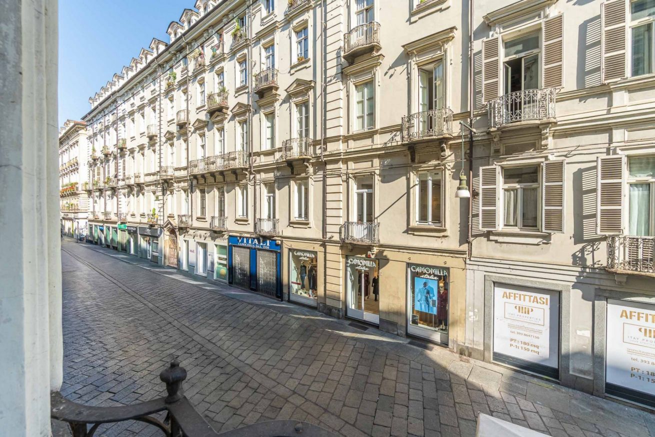 A row of traditional European buildings with storefronts, including visible signage for a hotel and other businesses.