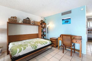 Ein Zimmer mit einem Bett, einem Schreibtisch, einem Sessel, einem Bücherregal und einem Bild an der Wand.