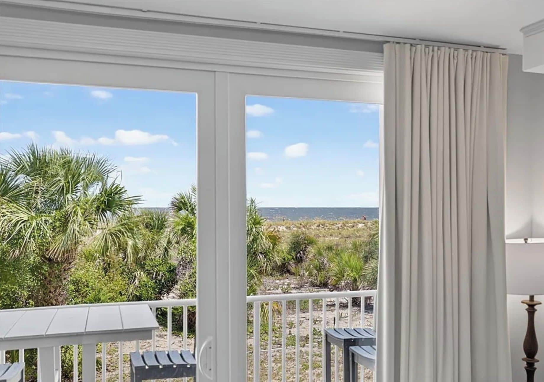 A balcony with a view of the beach and vegetation.