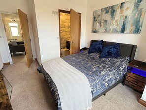 A bedroom with a bed, a nightstand, a desk, a chair, and a painting on the wall. - Beautiful 1-Bedroom City Retreat (Sheffield)
