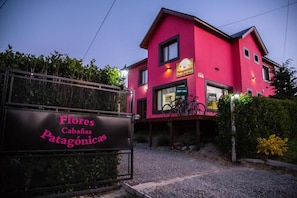Edifício rosa com placa indicando 'Flores Cabañas Patagonia' e uma bicicleta estacionada em frente.